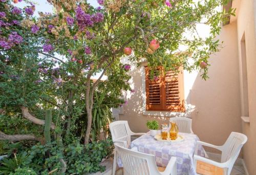 a table and chairs in a garden with flowers at Apartments Longo in Supetar