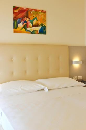 a bedroom with a white bed with a painting on the wall at Hotel Belvedere in Manerba del Garda