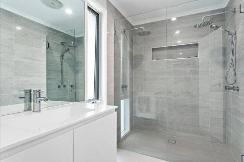 La salle de bains est pourvue d'un lavabo et d'une douche avec une porte en verre. dans l'établissement Luxurious 5 bedroom Villa with hot tub & much more, à Rosebud