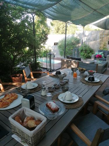 Una mesa de madera con platos de comida encima. en Chambre d'hôtes Les Magnolias, en Pontpierre