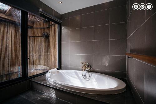 a bath tub in a bathroom with a window at Kongkarn Resort and Farmstay in Ban Pak Ngam