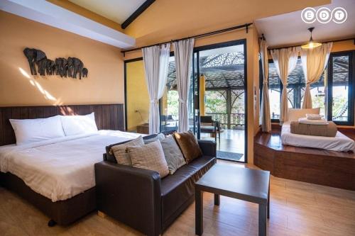 a bedroom with a bed and a chair and a couch at Kongkarn Resort and Farmstay in Ban Pak Ngam