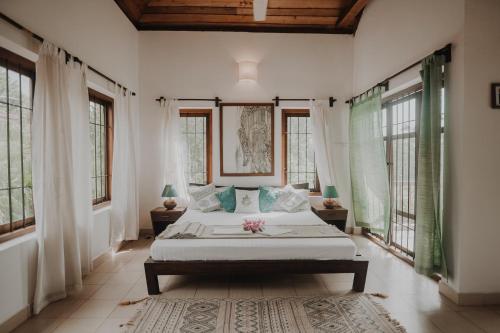 1 dormitorio con 1 cama en una habitación con ventanas en Villa Akasa, en Varkala