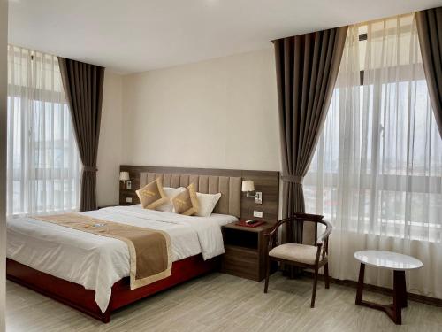 a bedroom with a bed and a chair and windows at Da Huong Hotel in Thái Nguyên