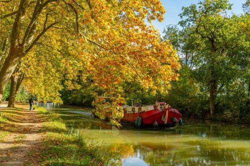 ein rotes Boot im Wasser auf einem Fluss in der Unterkunft LE DALLAS - 1 chambre, 1 canapé-lit, 1er étage, parking, 10min Canal du Midi in Castelsarrasin