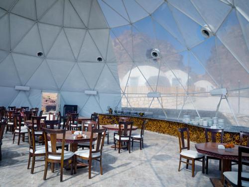 a dining room with tables and chairs and a large glass wall at The Rock Camp Petra in Wadi Musa