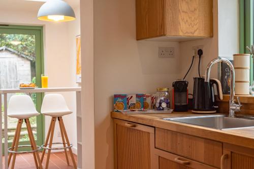 a kitchen with a sink and a counter with stools at Cosy 2 Bedroom Reading House SLEEPS 6 - With FREE WiFi & Garden by Roost Accommodation in Reading