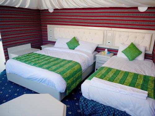 a room with two beds with green and white at The Rock Camp Petra in Wadi Musa