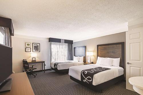 a hotel room with two beds and a desk at La Quinta by Wyndham Austin at The Domain in Austin