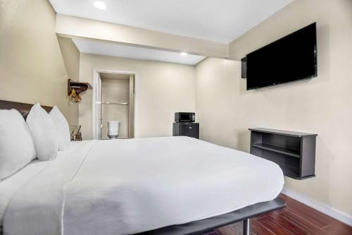 a bedroom with a large white bed and a flat screen tv at Motel 6-Ukiah, CA - North in Ukiah