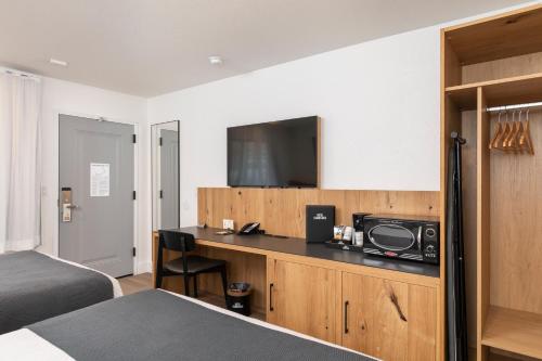 a hotel room with a bed and a desk with a television at Hotel Lumberjack - Sonora in Sonora