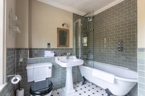 a bathroom with a sink and a tub and a toilet at The Running Horses in Mickleham