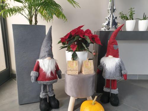 three gnomes standing next to a vase with flowers at Chalet le logis des autre in Vireux-Wallerand