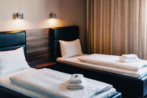 two beds in a hotel room with towels on them at Penzion v jízdárně in Olomouc