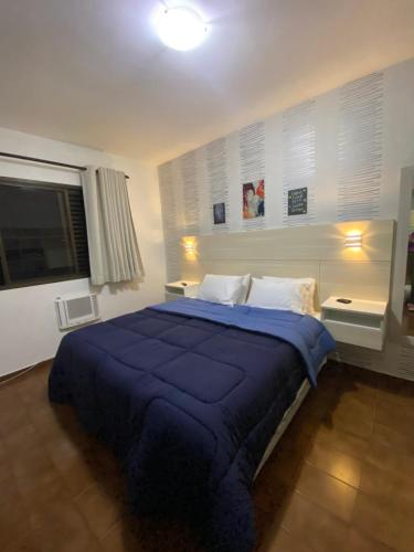 a bedroom with a large bed with a blue blanket at Guarujá Flat in Guarujá