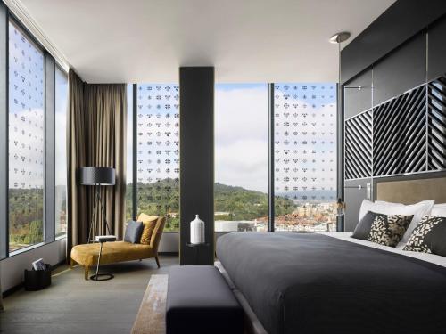 a bedroom with a large bed and a chair and windows at InterContinental - Ljubljana by IHG in Ljubljana
