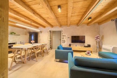 a living room with a table and blue chairs at Luxury Jerini House with pool and wellness in Bajčići