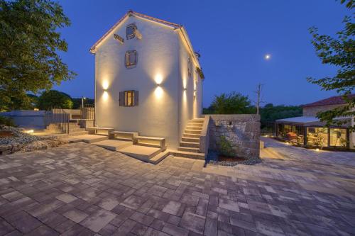 a small white building with stairs in front of it at Luxury Jerini House with pool and wellness in Bajčići