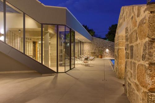an external view of a house with a stone wall at Luxury Jerini House with pool and wellness in Bajčići