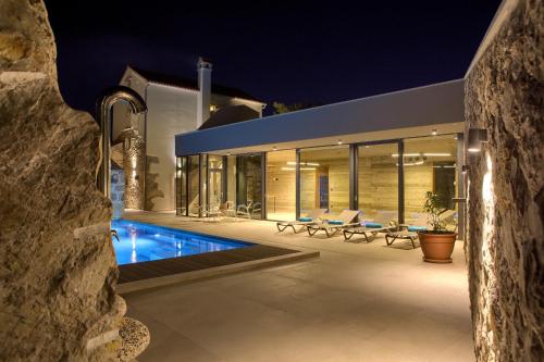 a house with a swimming pool at night at Luxury Jerini House with pool and wellness in Bajčići