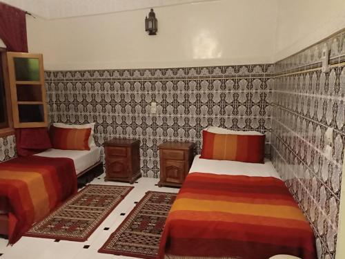 a room with two beds and a wall with patterns at Dar HAJAR in Marrakech
