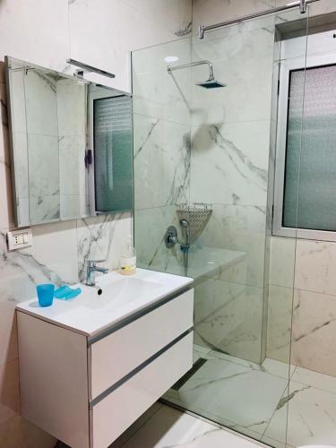 bagno bianco con lavandino e doccia di Saranda Port View Apartments a Sarandë