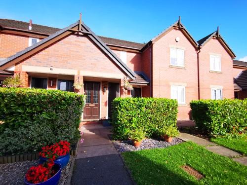 una casa con arbustos y flores delante de ella en The Roman Retreat en Chester