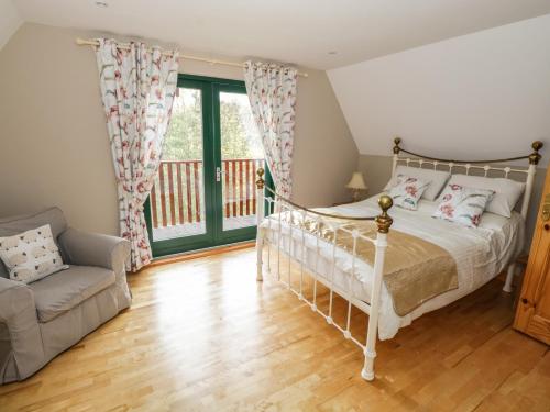 a bedroom with a bed and a couch and a window at 12 Cornadarragh in Belturbet
