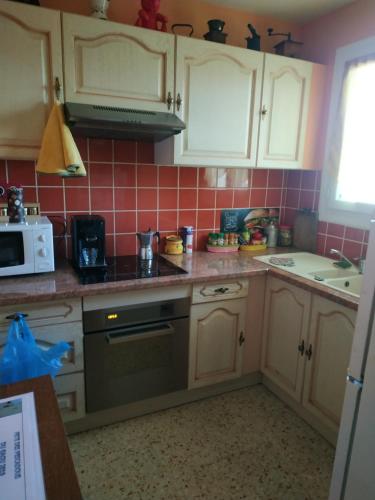 une cuisine avec des armoires blanches et un four à plaques de cuisson dans l'établissement Six Fours les Plages T2, à Six-Fours-les-Plages