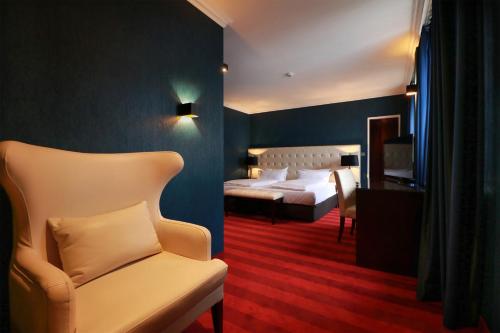 a hotel room with two beds and a chair at Hotel Haverkamp in Bremerhaven