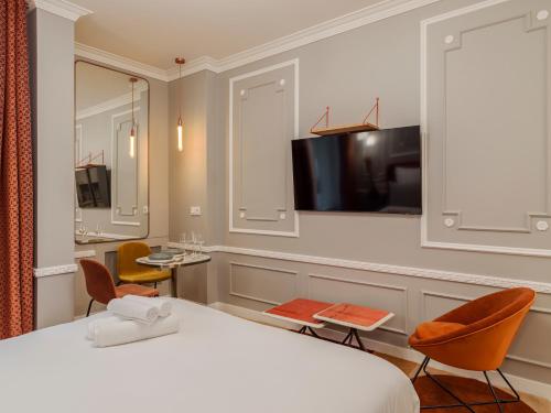 a hotel room with a bed and a tv at The Orange Haussmann in Paris