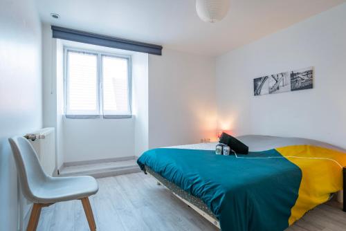 ein Schlafzimmer mit einem Bett und einem Stuhl und einem Fenster in der Unterkunft Gite Le Carpe Diem - Classé 3 étoiles - Parking, wifi, jeux société in Marmoutier