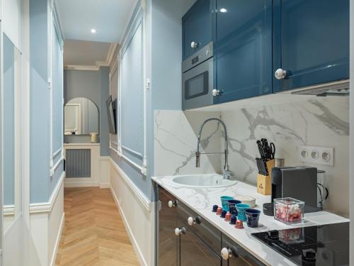 une cuisine avec des armoires bleues et un évier dans l'établissement The Pompadour Suite, à Paris