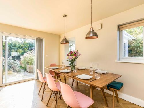 a dining room with a wooden table and pink chairs at Stylish and fresh 4 bed beach house with garden - Pass the Keys in Chichester