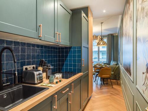 a kitchen with green cabinets and a sink and a dining room at Nature and Haven of Peace Apartment in Paris