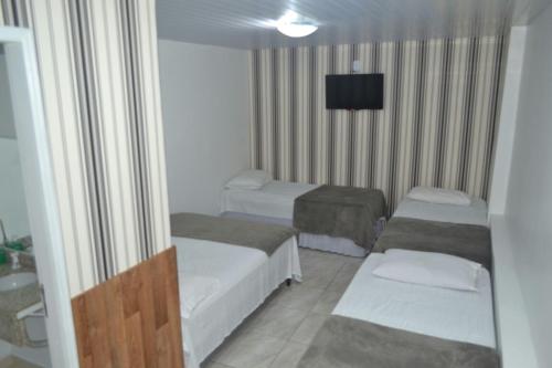 a hotel room with two beds and a television at Pousada São Judas Tadeu in Cachoeira Paulista