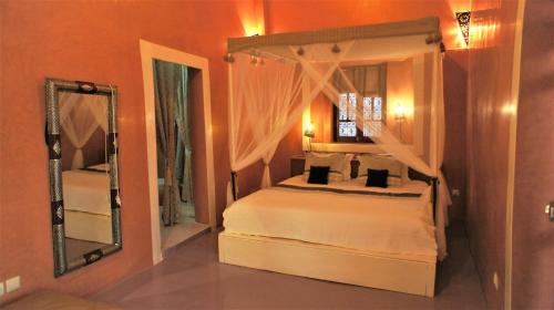 a bedroom with a canopy bed and a mirror at Riad Alqimam in Marrakesh