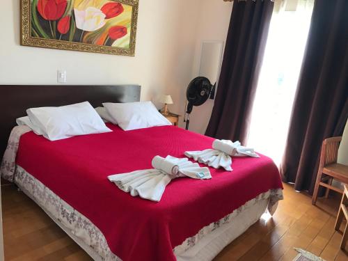 1 dormitorio con 1 cama grande con sábanas rojas y toallas blancas en Pousada Bosque das Araucárias, en Campos do Jordão