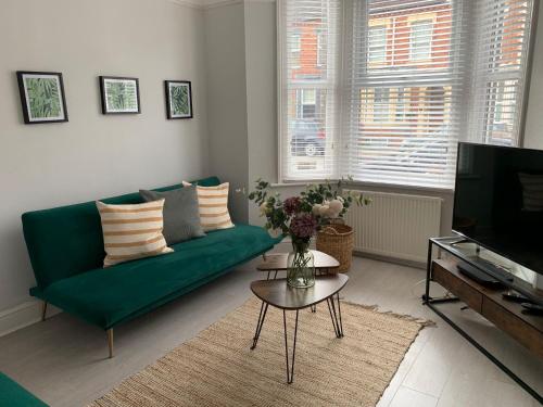 a living room with a green couch and a tv at House of cosy dots in Northampton