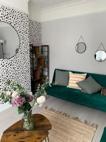 a living room with a green couch and a vase of flowers at House of cosy dots in Northampton