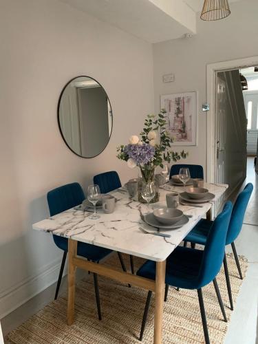 a dining room table with blue chairs and a mirror at House of cosy dots in Northampton