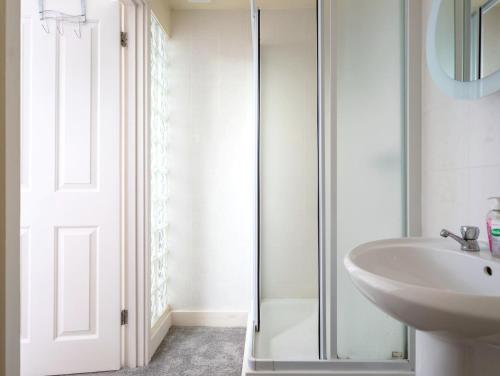 a bathroom with a sink and a glass shower door at The Annexe in Cheltenham