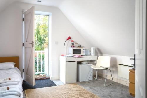 a bedroom with a bed and a desk with a microwave at The Annexe in Cheltenham