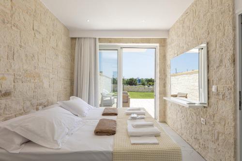 a bedroom with a large white bed and a window at Mythos villas in Damnoni