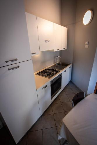 a kitchen with white cabinets and a stove top oven at Albavillage Hotel Wellness & Camping in Alba
