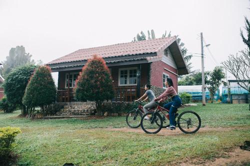 dos personas montando bicicletas delante de una casa en Phoomtada Homestay en Wiang Pa Pao