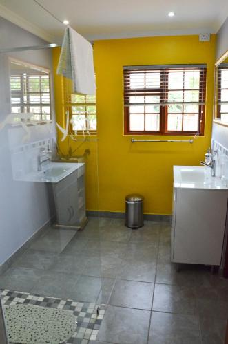 a bathroom with two sinks and a yellow wall at Kleinbosch Lodge in Stellenbosch