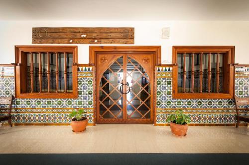 a large wooden door in a room with two potted plants at Balneario San Nicolas in Alhama de Almería