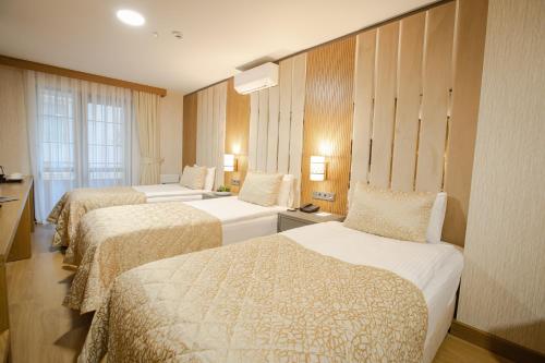 a hotel room with three beds and a window at bahçelievler hotels in Ankara
