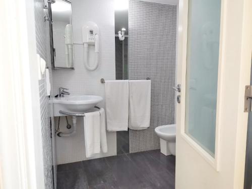 a white bathroom with a sink and a toilet at Unique Apartment Milfontes - Duna Parque Resorts & Hotels in Vila Nova de Milfontes